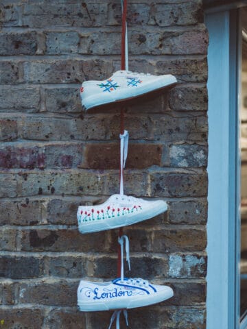 3 white sneakers hanging by shoestrings on a wall to represent HR on shoestring and free HR resources