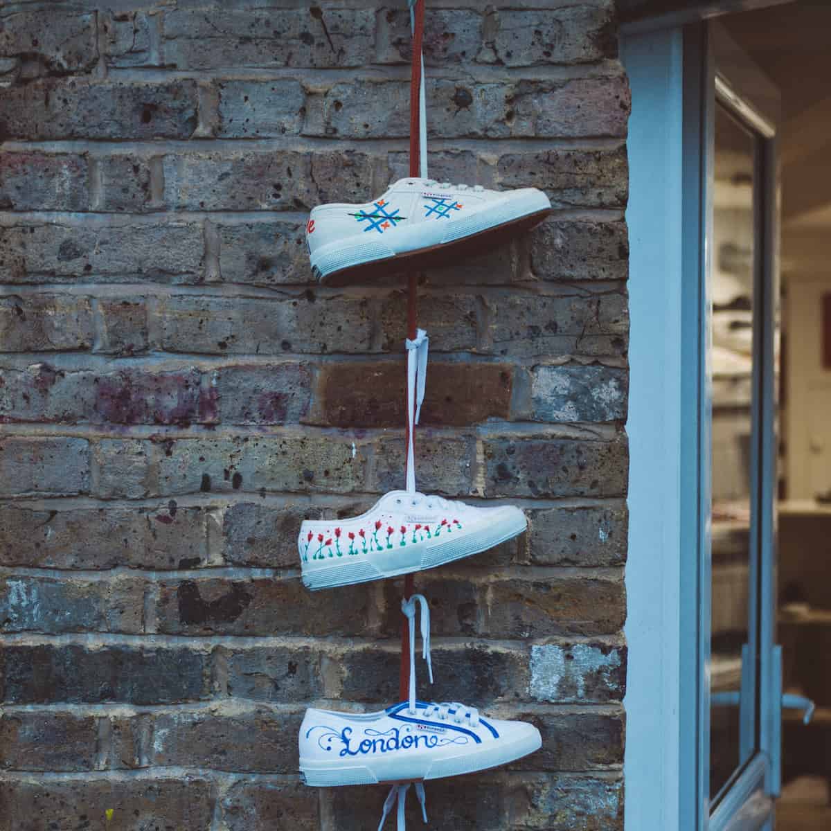 3 white sneakers hanging by shoestrings on a wall to represent HR on shoestring and free HR resources