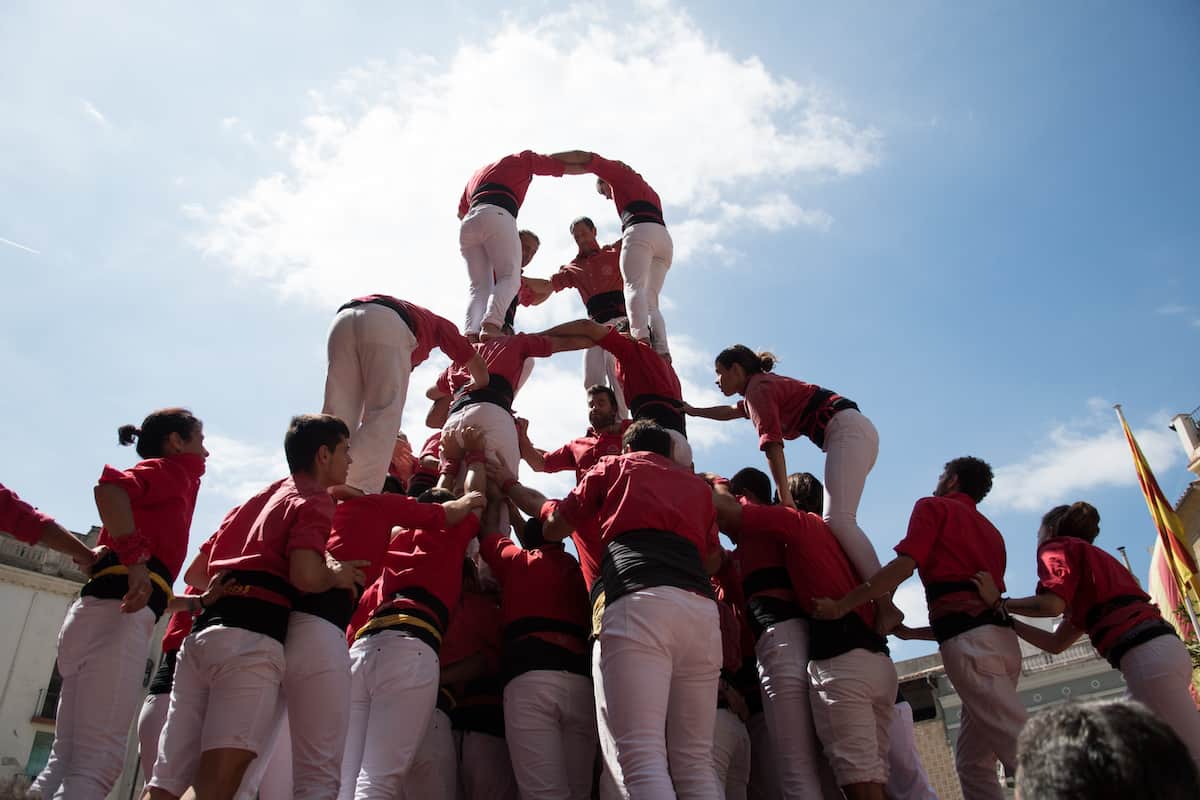 human pyramid, everyone in white pants and red tops