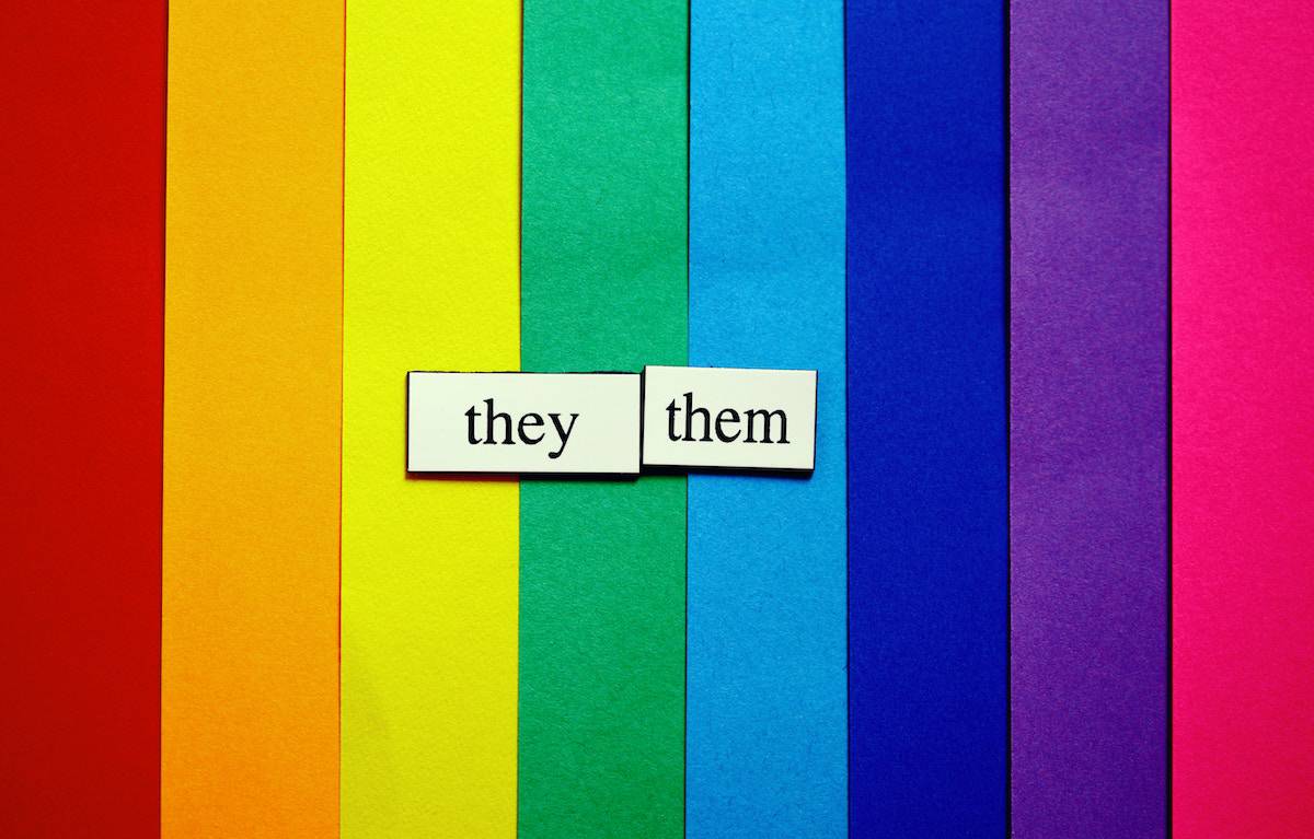 they them type on tiles sitting on a rainbow background